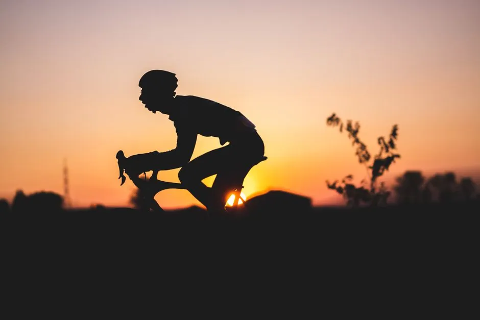 Silhouette d'un cycliste sur fond de coucher de soleil